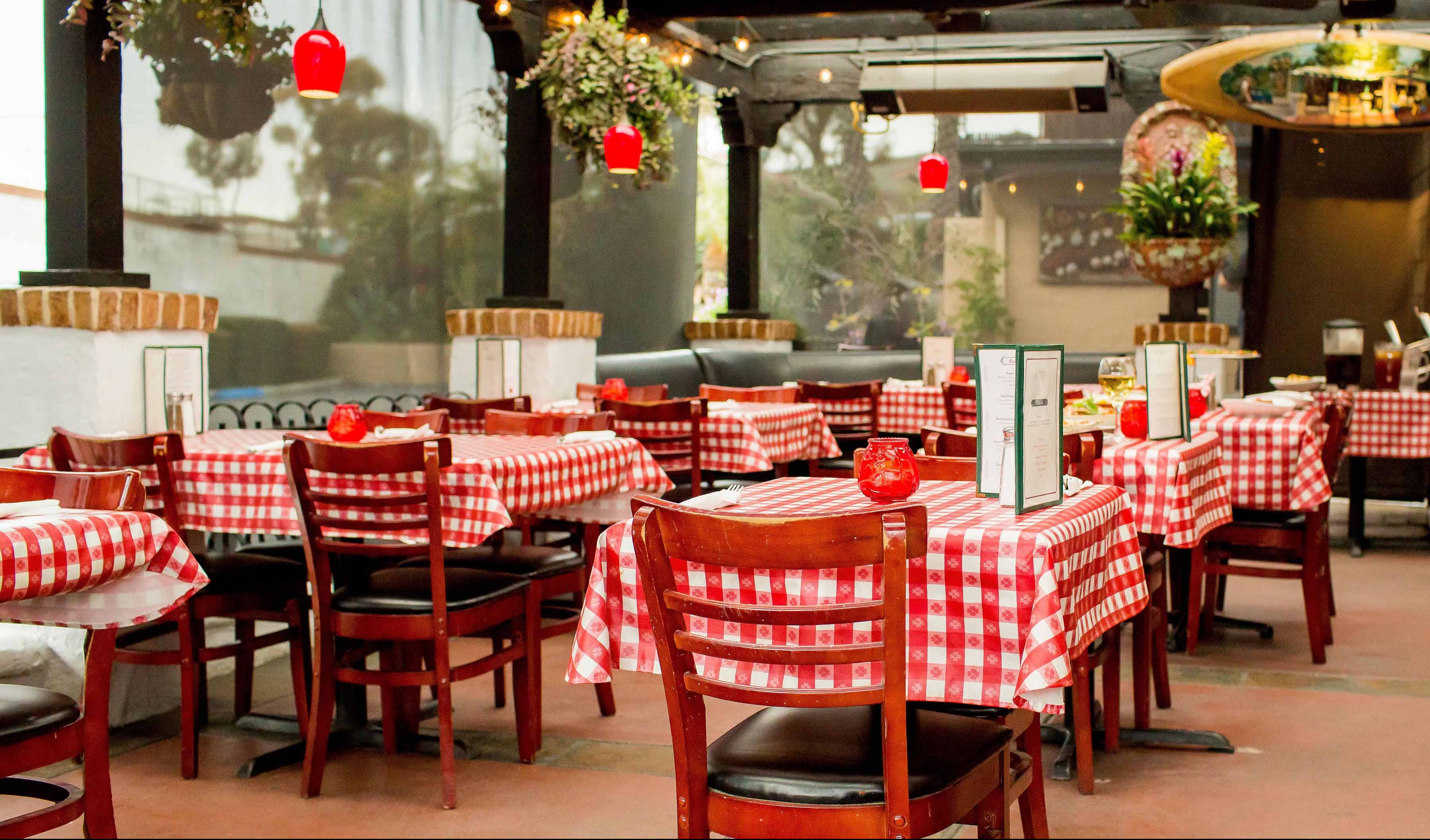 Sonny's Outdoor Covered patio seating with red and white table clothes and hanging lights